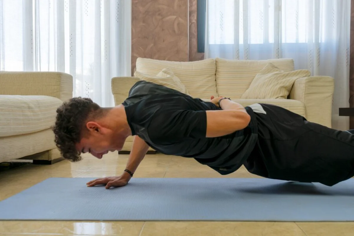 Young man performing a push-up in a living room, focusing intently on his fitness routine.