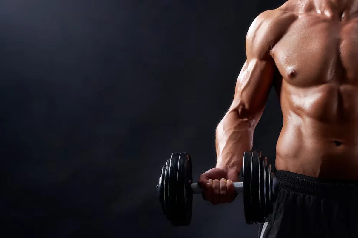 Muscular man performing a bicep curl with a heavy dumbbell in a gym setting.
