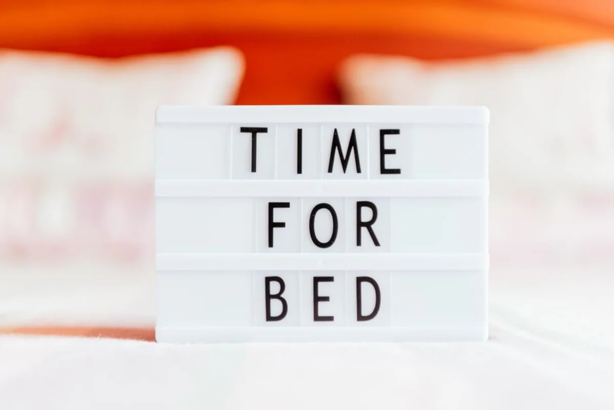 Lightbox sign with the words TIME FOR BED in front of a blurred orange pillow.
