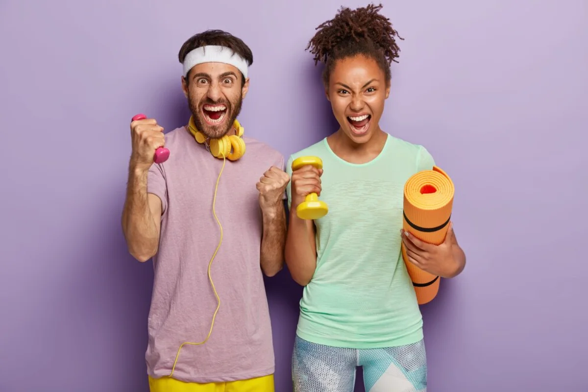 Two joyful people holding exercise equipment, one with a yoga mat, against a purple background.