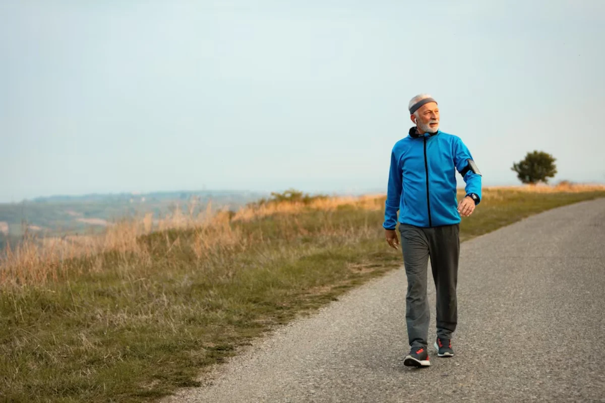 Elderly man in a blue jacket enjoying a leisurely walk along a countryside road.