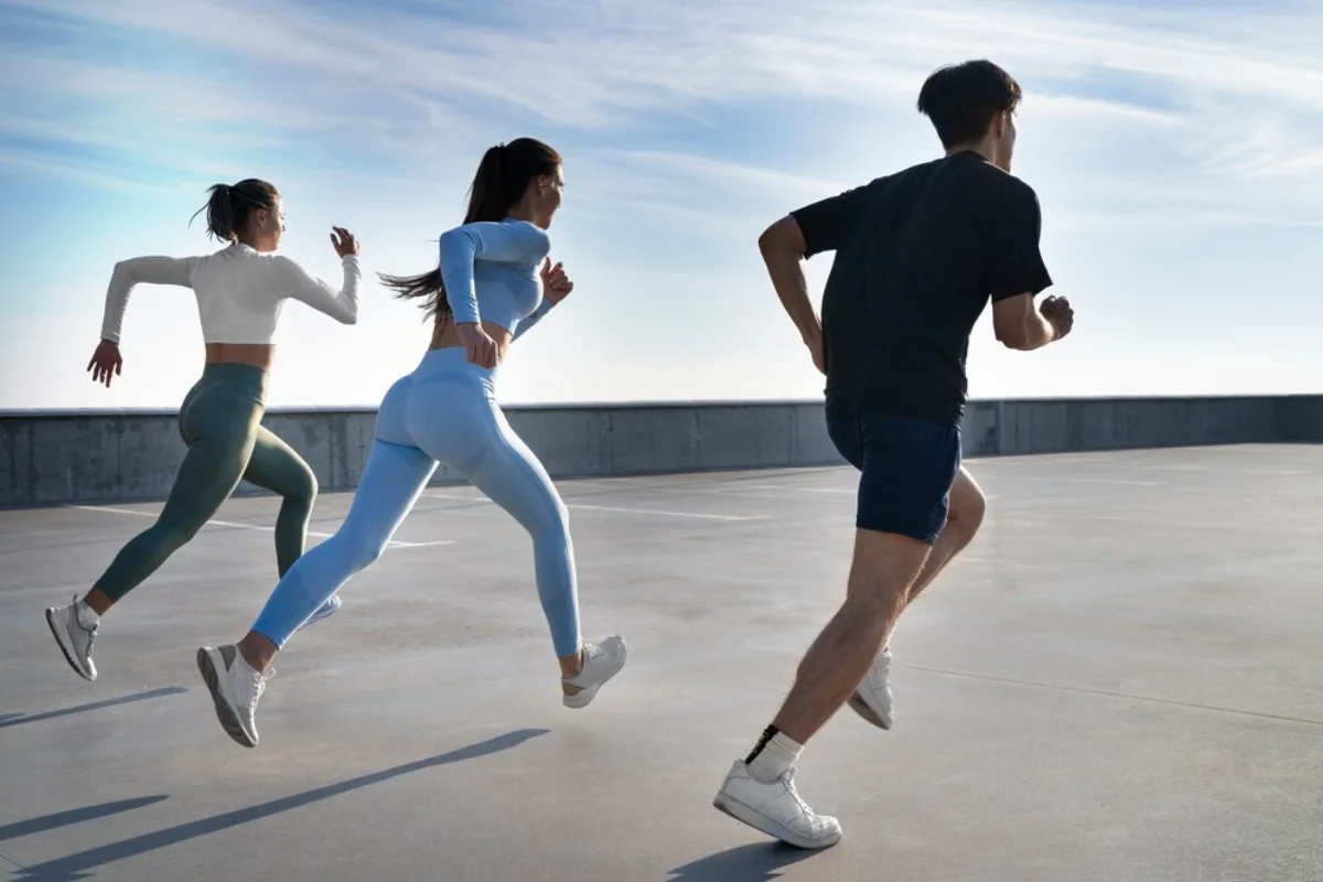 Three people running on a rooftop, with a clear blue sky in the background.