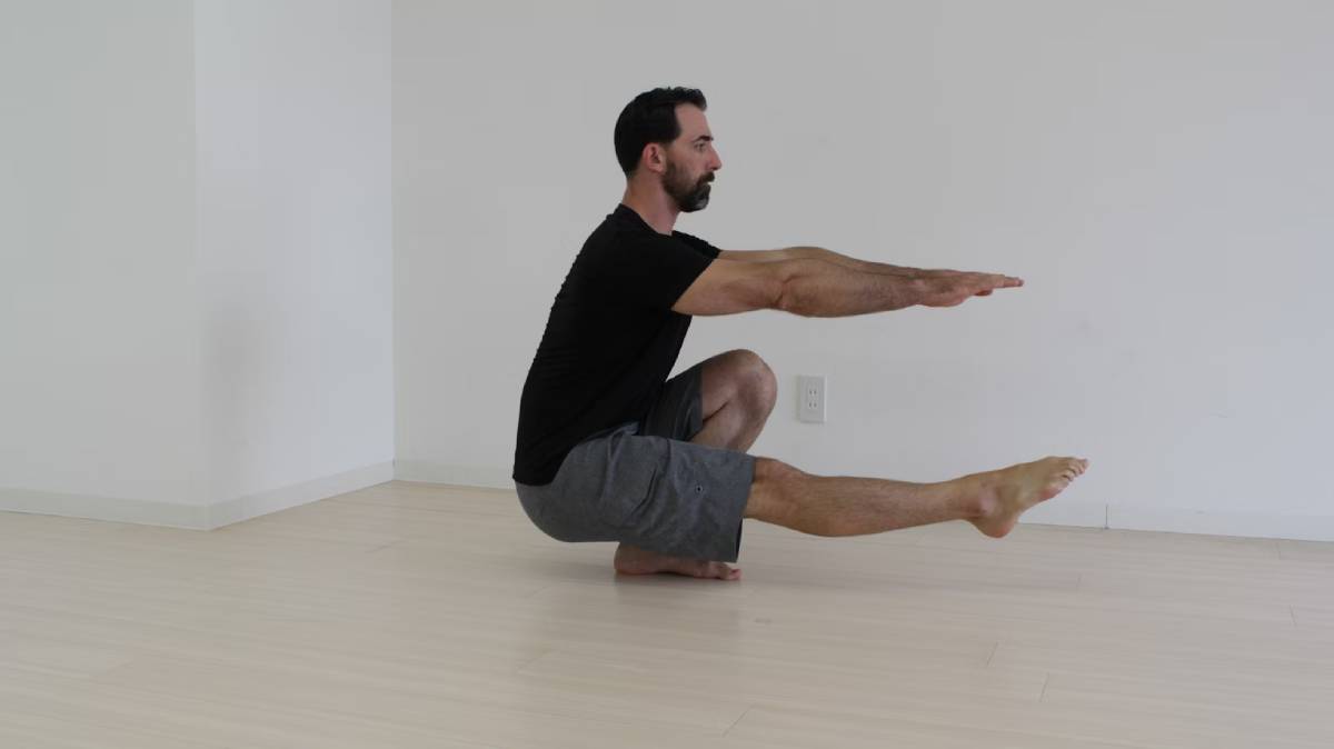 Man performing a balancing yoga pose in a bright, minimalist room.